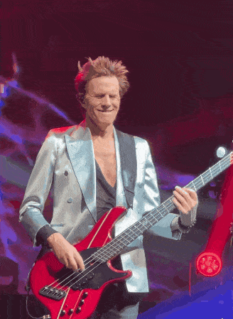 a man playing a red bass guitar on a stage