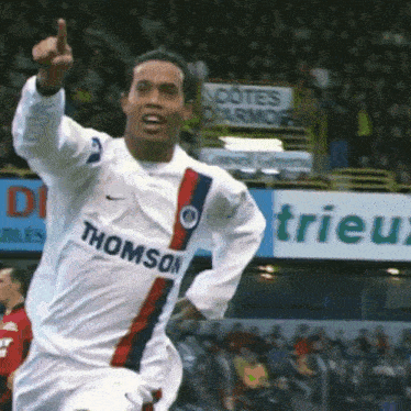 a soccer player wearing a thomson jersey is pointing up