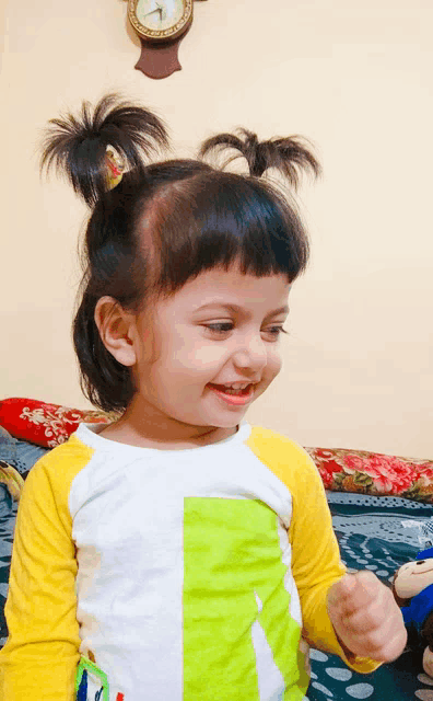 a little girl with pigtails and a clock behind her