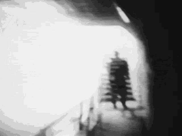 a black and white photo of a silhouette of a person in a tunnel .