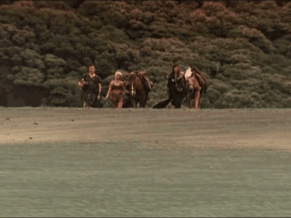 a group of people are walking on a beach with horses
