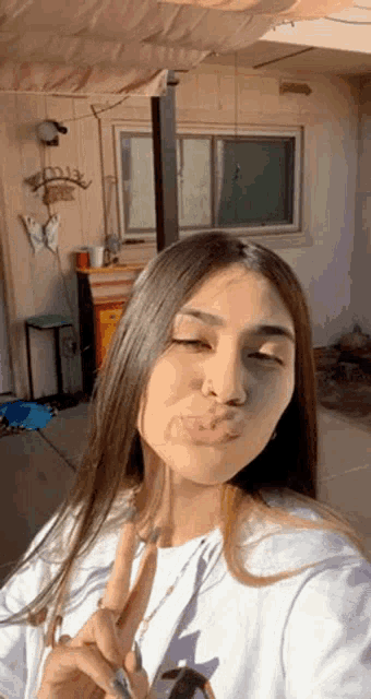 a woman is taking a selfie and making a peace sign with her hand .