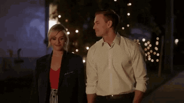 a man and a woman are walking down a street at night .