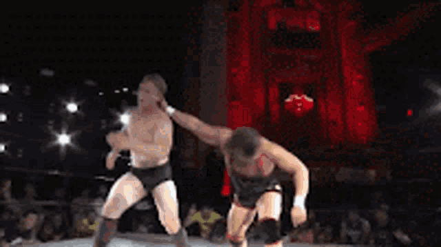 two wrestlers are fighting in a ring with a sign that says alvarez in the background