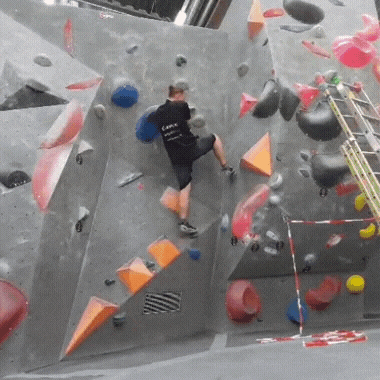 a man is climbing a climbing wall with a ladder in the background .