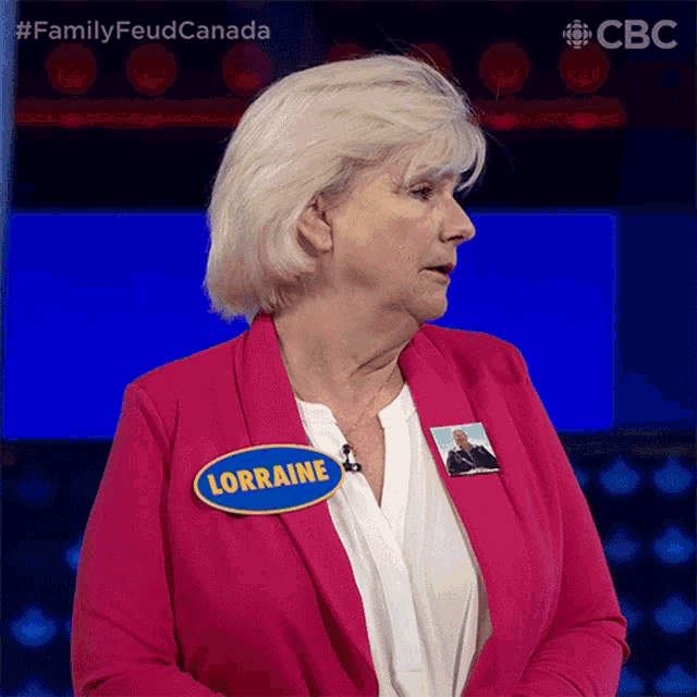 a woman wearing a pink jacket has a name tag that says lorraine