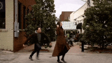 a man and woman are running down a street