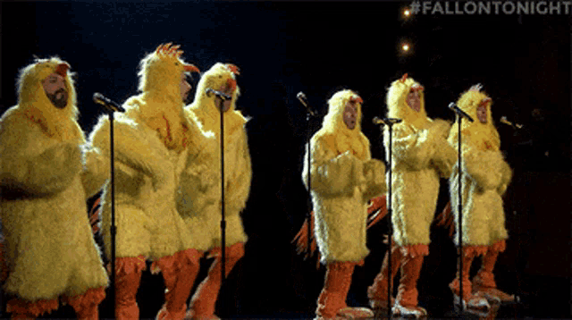 a group of people dressed in chicken costumes singing into microphones