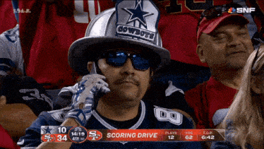 a cowboys fan wearing a fireman 's helmet talks on a cell phone