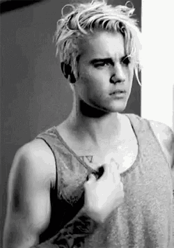 a black and white photo of a young man with blonde hair wearing a tank top .