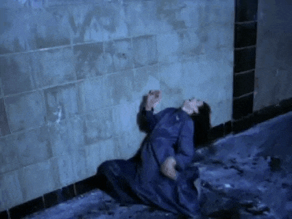 a woman in a blue dress is crawling on the floor in a dark room .