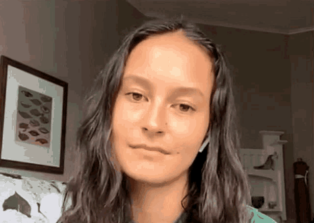 a woman with long hair and headphones is sitting on a couch in front of a framed picture .