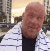 a bald man with a beard and a towel around his neck is smiling .
