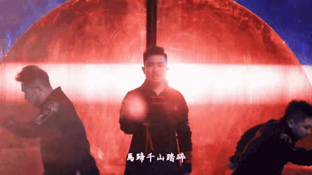 a man in a black jacket stands in front of a red background with chinese writing