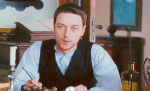 a man in a vest is sitting at a table with a pen in his hand