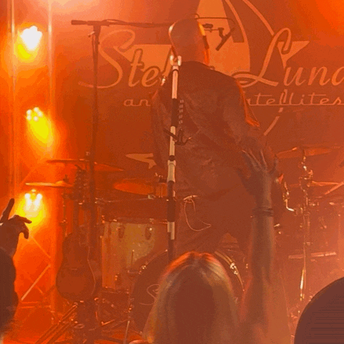 a man playing a guitar in front of a sign that says stella lune satellite