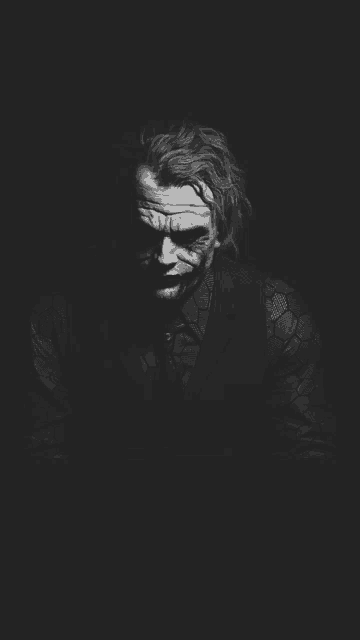 a black and white photo of the joker in a suit and tie .