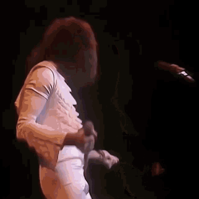 a woman is singing into a microphone on a stage .