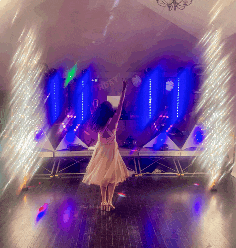 a girl in a white dress stands in front of a stage that says happy birthday
