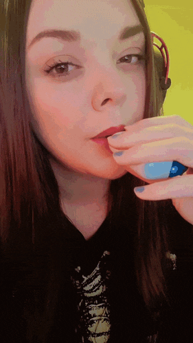 a woman wearing headphones and a blue nail polish holds a blue object in her hand