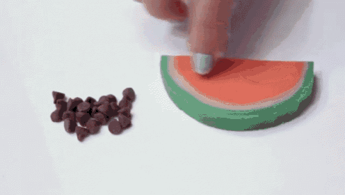 a person is putting chocolate chips on a watermelon slice