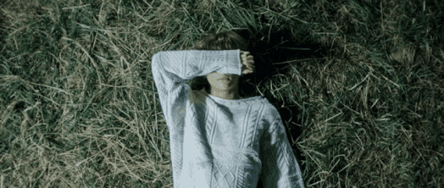 a person in a sweater is laying in the grass