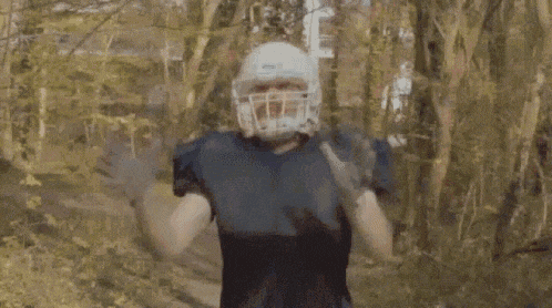 a man wearing a football helmet and gloves is throwing a football in the air