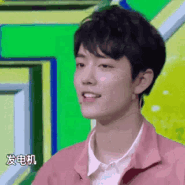 a young man wearing a pink jacket and white shirt is smiling .