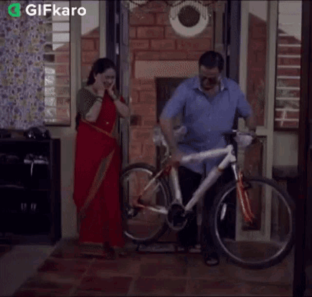 a man and a woman are standing next to a bicycle with gifkaro written on the bottom right
