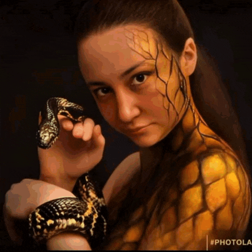 a woman with body paint holding a snake with the hashtag #photola at the bottom