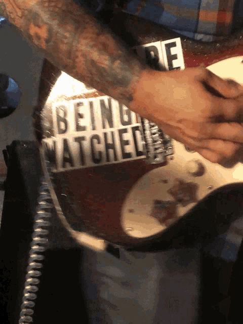 a man playing a guitar with a sticker that says being matched