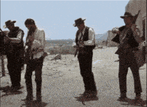 a group of men are standing on a dirt road
