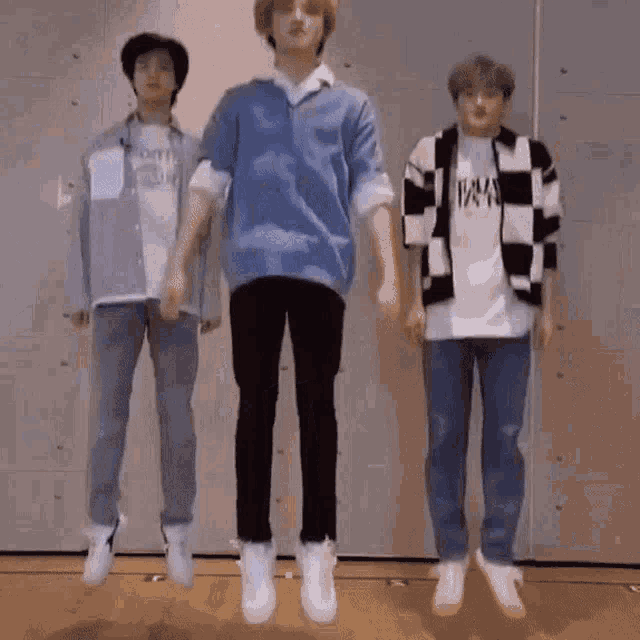 three young men are jumping in the air together .