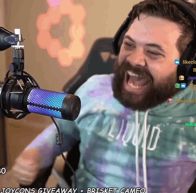 a man with a beard is screaming into a microphone while wearing headphones and a shirt that says hollywood