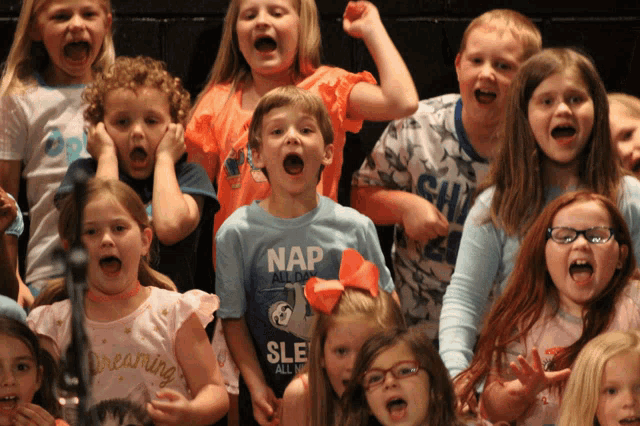 a boy in a nap shirt is surrounded by children