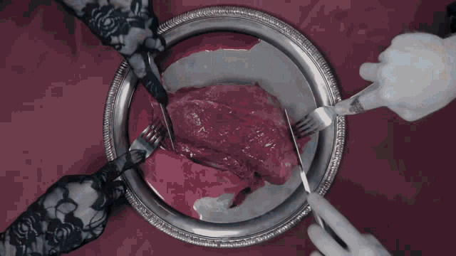 a person is cutting a piece of meat on a plate with a knife and fork