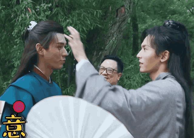 two men are standing next to each other and one has a fan