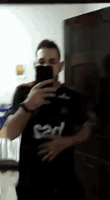 a man taking a picture of himself in a mirror while wearing a shirt that says bd