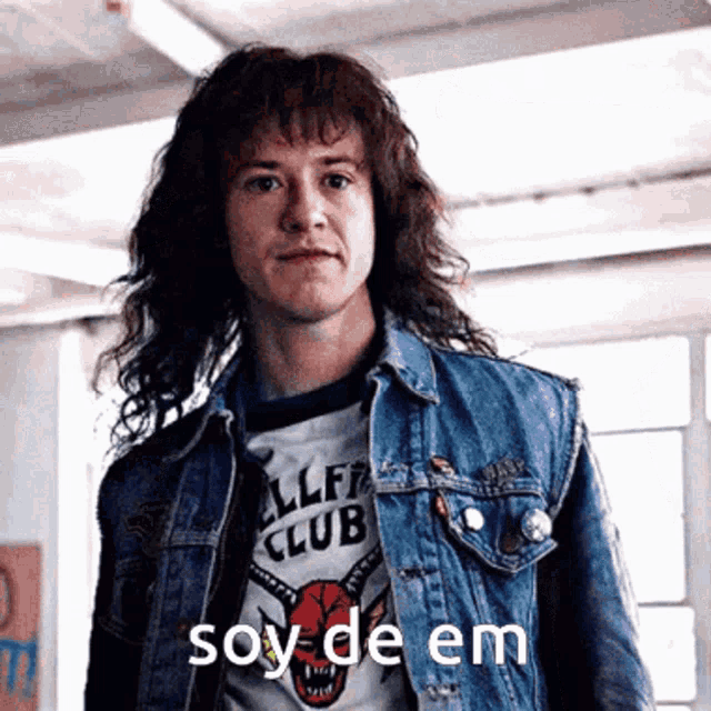 a man with long hair wearing a denim jacket and a shirt that says cliff club