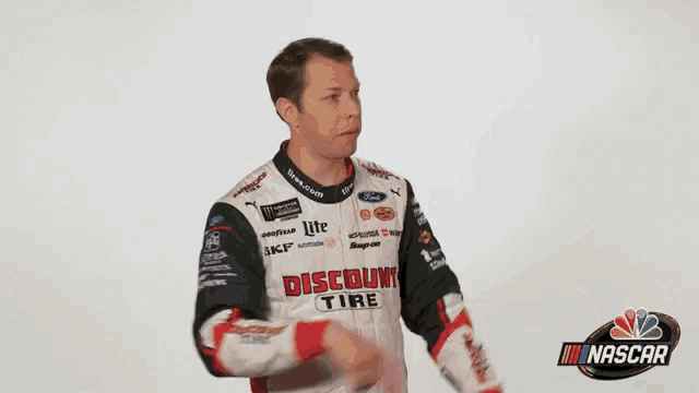 a man wearing a jacket that says discount is standing in front of a nascar logo