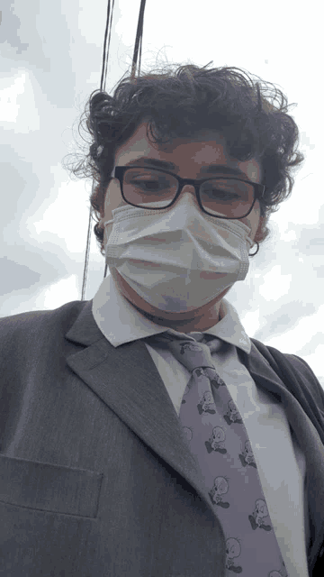 a man wearing a suit and tie with a face mask on his face