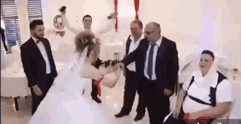 a bride and groom are dancing at their wedding reception while a group of men watch .