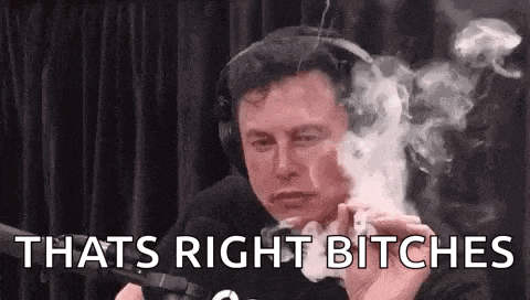 elon musk is smoking a cigarette in front of a microphone .