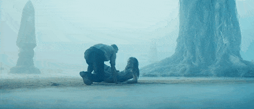 a man is kneeling down next to a woman who is laying on the ground .