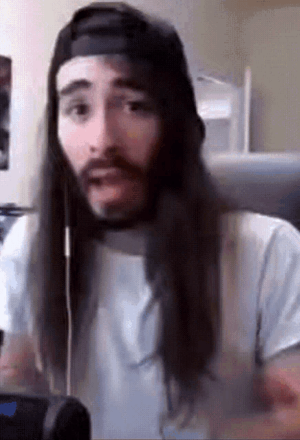 a man with long hair and a beard is wearing a hat and headphones