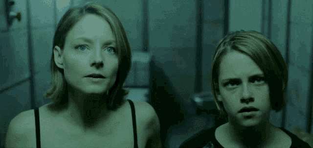 two women are standing next to each other in a dark room