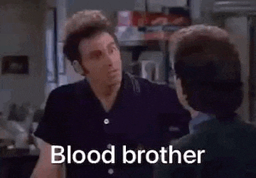 a man in a black shirt is talking to another man in a kitchen while saying `` blood brother '' .
