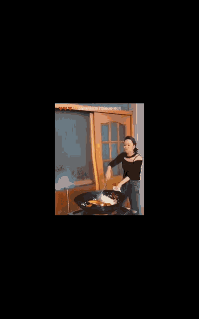 a woman is stirring food in a frying pan while a fire is coming out of it
