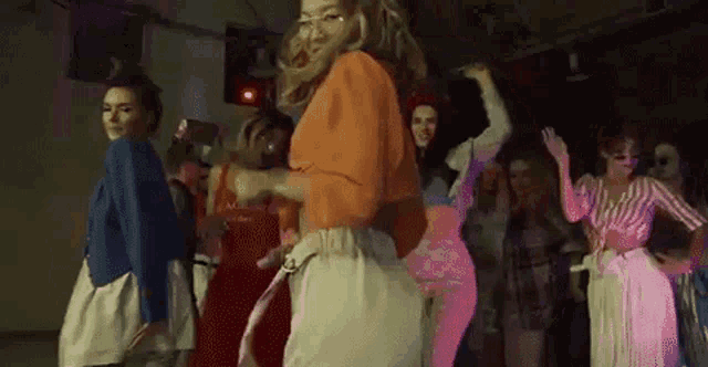 a group of women are dancing together in a dark room in a club .