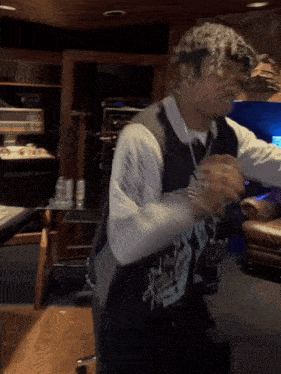 a man wearing a vest that says ' snoop dogg ' on it is standing in a room